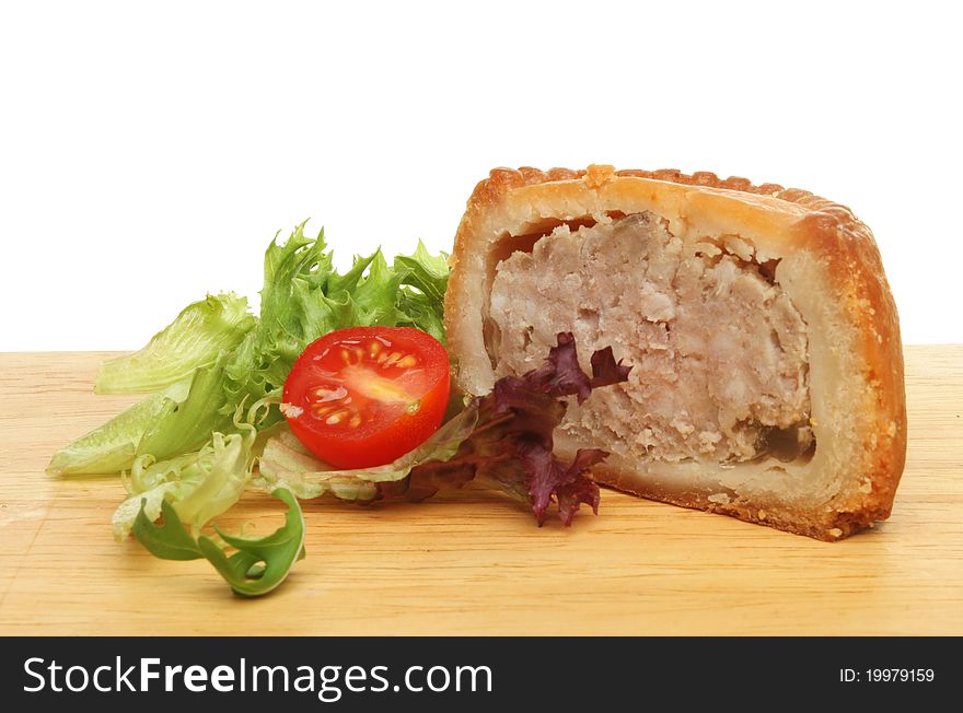 A portion of pork pie with salad garnish on a wooden food preparation board