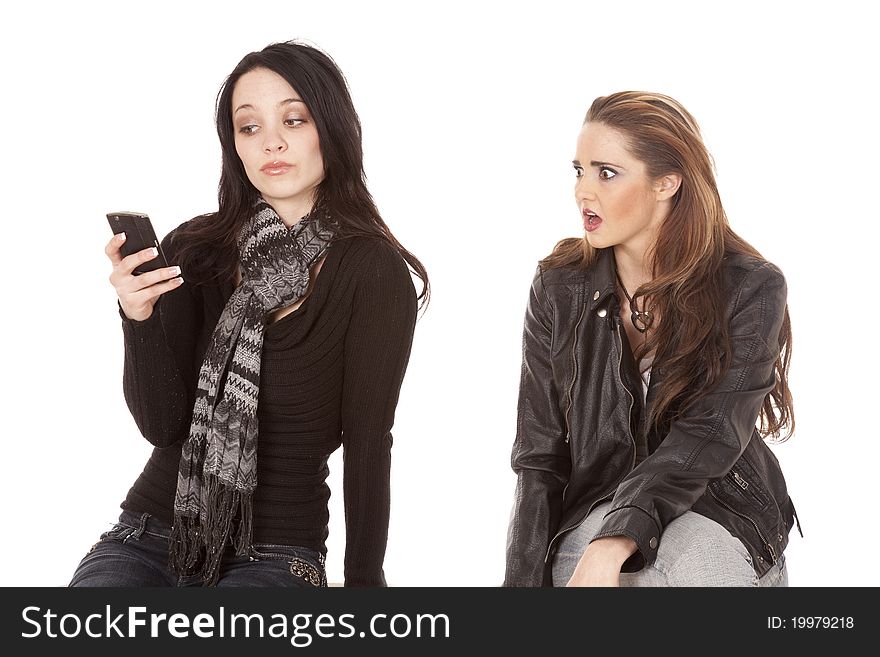 A women is showing her shocked expression on her face at what the other women is texting on her phone. A women is showing her shocked expression on her face at what the other women is texting on her phone.