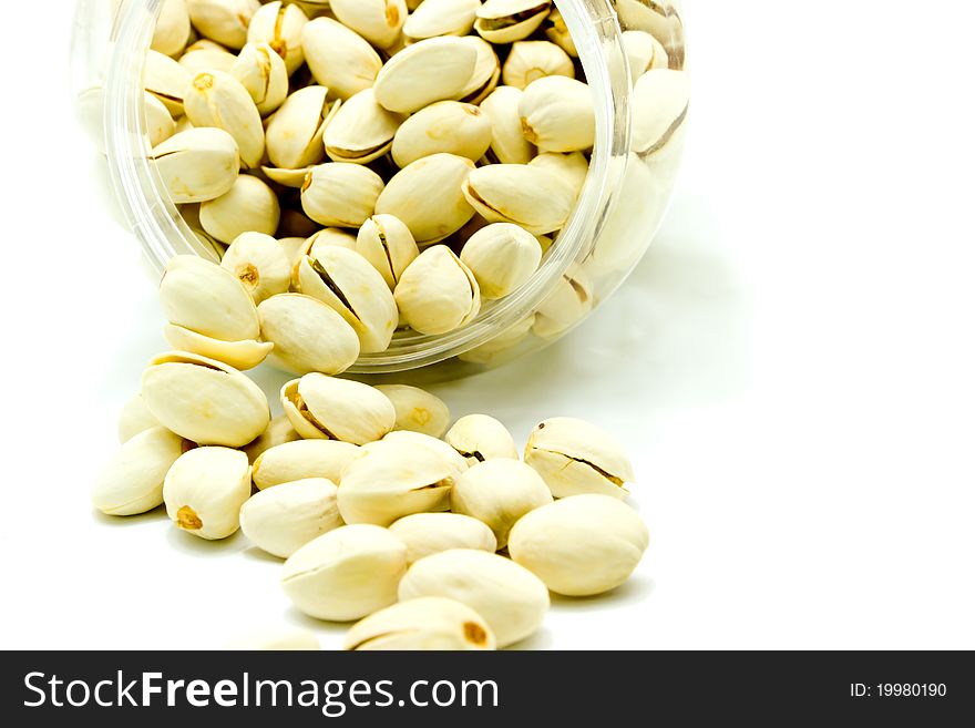 Pistachios pouring from jar on white background