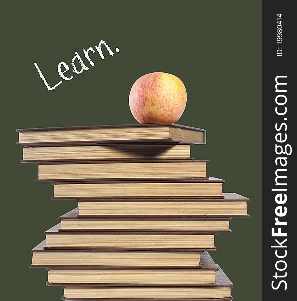 An apple on top of stack of books isolated on green. An apple on top of stack of books isolated on green