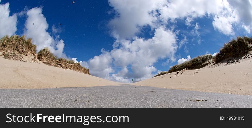 Walkway towards the beach with clouded blue sky