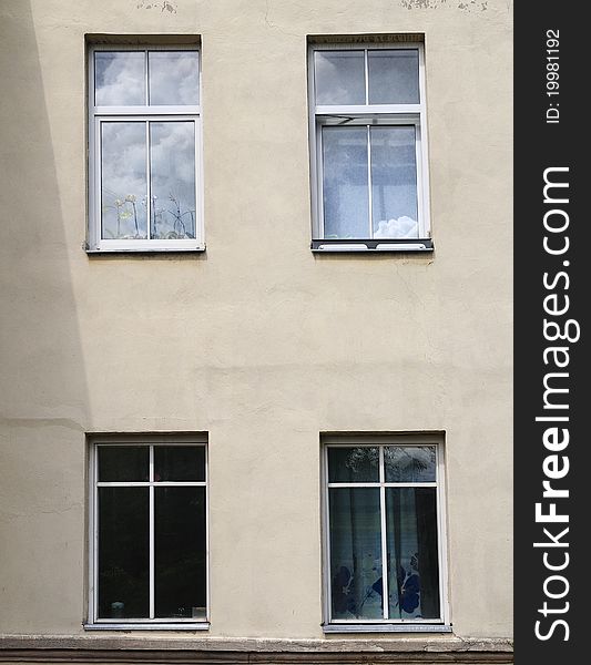 Four windows. In two windows the sky in clouds is reflected. Two other windows dark