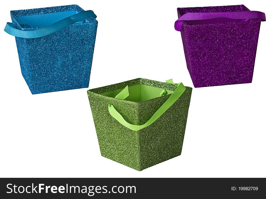 Multi-colored boxes with glitter and ribbon handles isolated on a white background. Multi-colored boxes with glitter and ribbon handles isolated on a white background.