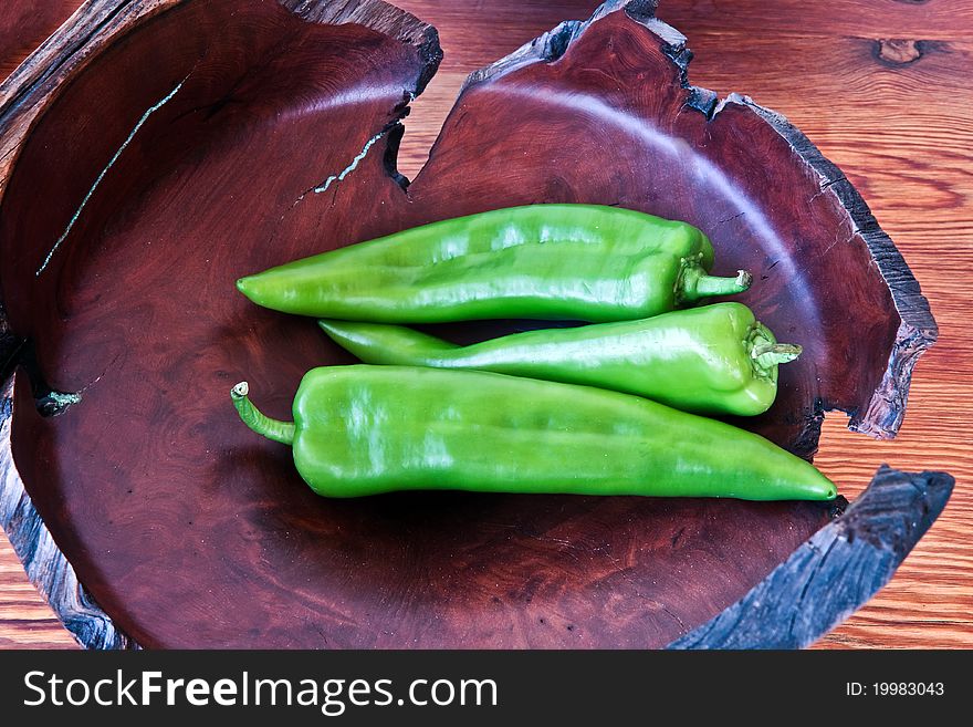 Serrano peppers in a burlwood bowl on a wood table