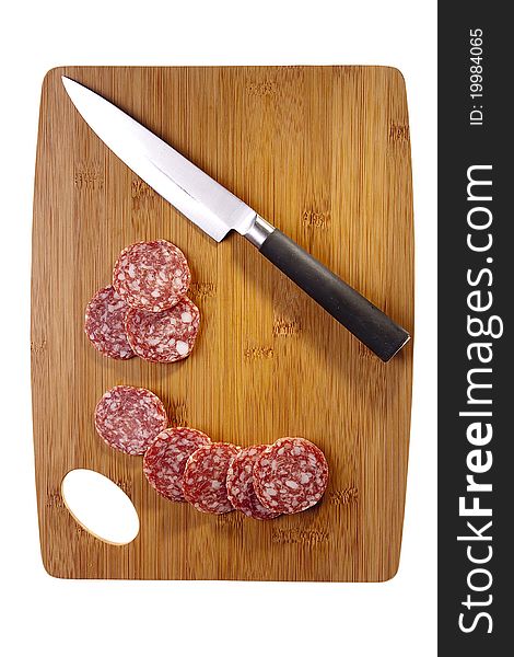Sliced salami laying next to a knife on a brown cutting board. Sliced salami laying next to a knife on a brown cutting board.
