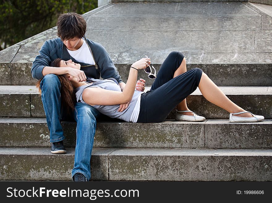 Portrait of young love couple sitting together on steps of a building