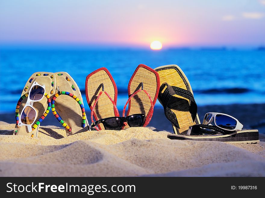 Three pair of beach sandals and glasses on the sandy beach. Three pair of beach sandals and glasses on the sandy beach