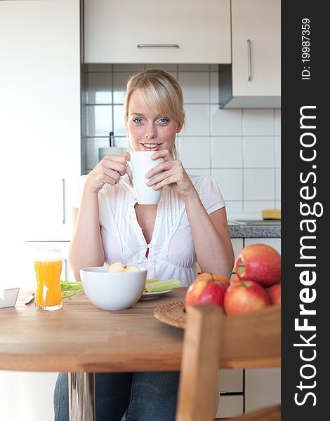 Young blond woman with her breakfast at a table in a kitchen