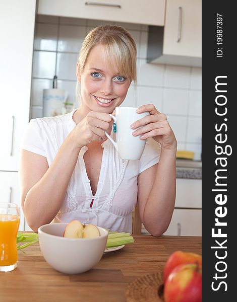 Young blond woman with her breakfast at a table in a kitchen