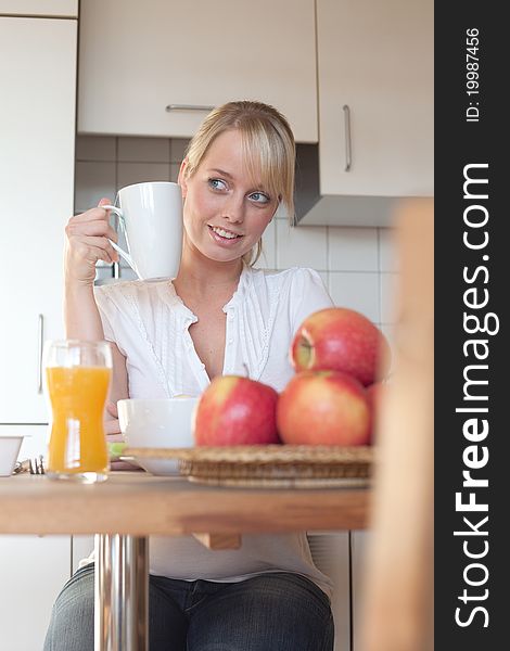Young blond woman with her breakfast at a table in a kitchen