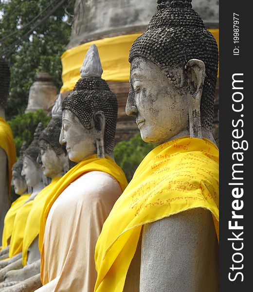 Buddha statues covered in yellow cloth sitting in a row in a ruined temple. Buddha statues covered in yellow cloth sitting in a row in a ruined temple