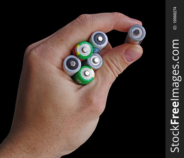 A mens hand holding a few AA batteries isolated on black. A mens hand holding a few AA batteries isolated on black