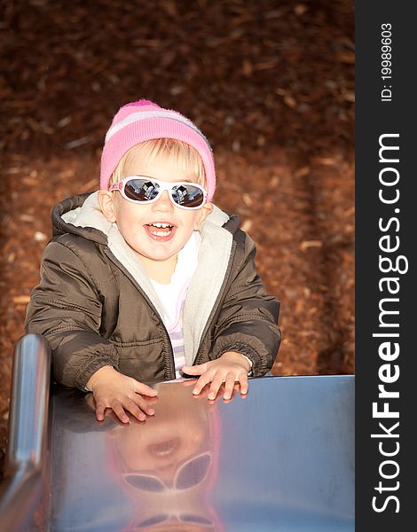 Little girl laughing at the bottom of a slippery slide. Little girl laughing at the bottom of a slippery slide