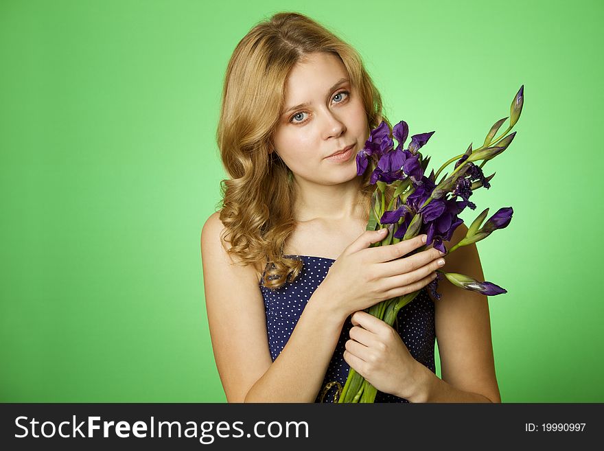Happy close-up on a green background Happy young woman hugging a blue iris. Young Woman Hugging Flower. Happy close-up on a green background Happy young woman hugging a blue iris. Young Woman Hugging Flower