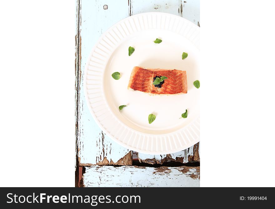 Grilled salmon fillet decorate with fresh herbs and caviar.