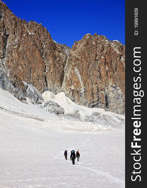 Climbers in the snowy mountains with rocks and deep blue sky