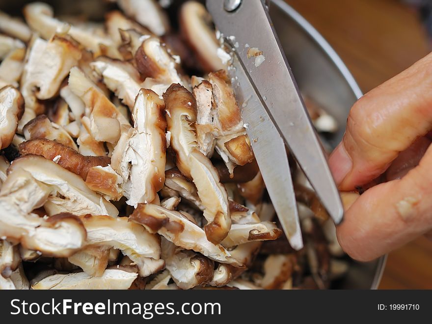 Scissors cutting fresh black mushrooms into tiny slices for food ingredients. Scissors cutting fresh black mushrooms into tiny slices for food ingredients.