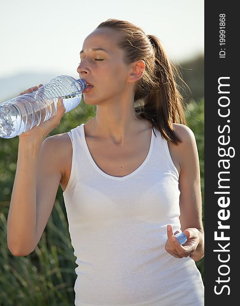 Fitness woman drinking water after workout