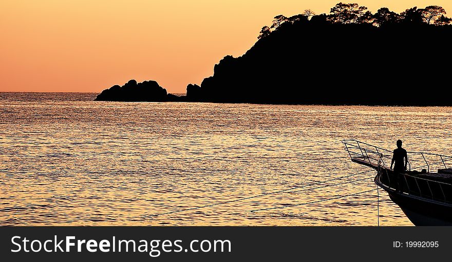 Sun setting behind a tropical island as a fisherman ties up his boat. Sun setting behind a tropical island as a fisherman ties up his boat.