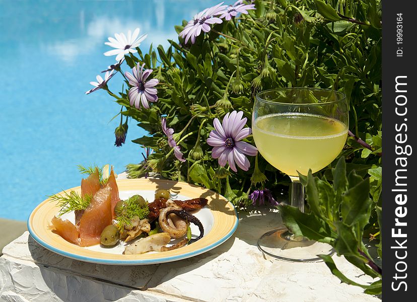 The dish with seafood salad and glass of lemon juice near poolside.Crete. Greece