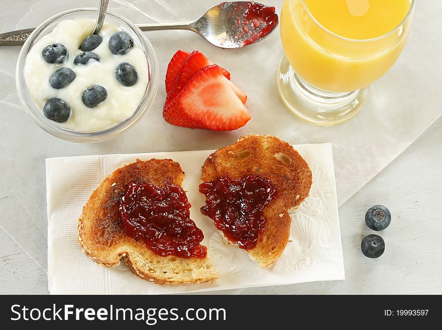 Quick breakfast consisting of orange juice, strawberroes. toast/jam, and blueberries w/yogurt. Quick breakfast consisting of orange juice, strawberroes. toast/jam, and blueberries w/yogurt.