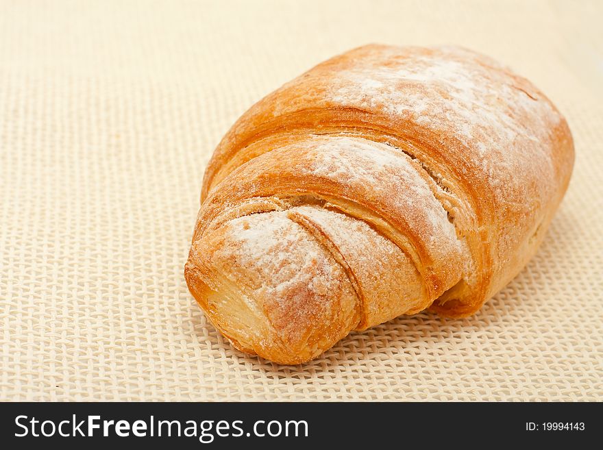 Croissant dusted with icing sugar over cloth