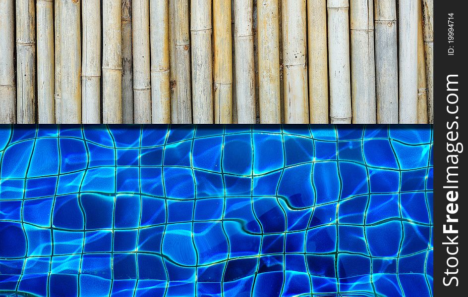 A bamboo floor next to a pool with blue tiles