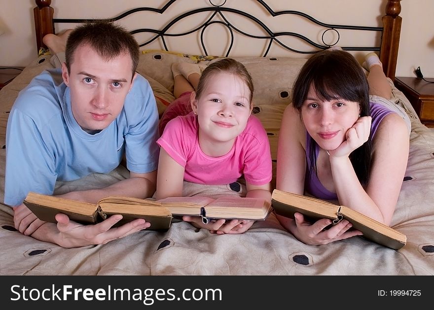 The family reads books in bed