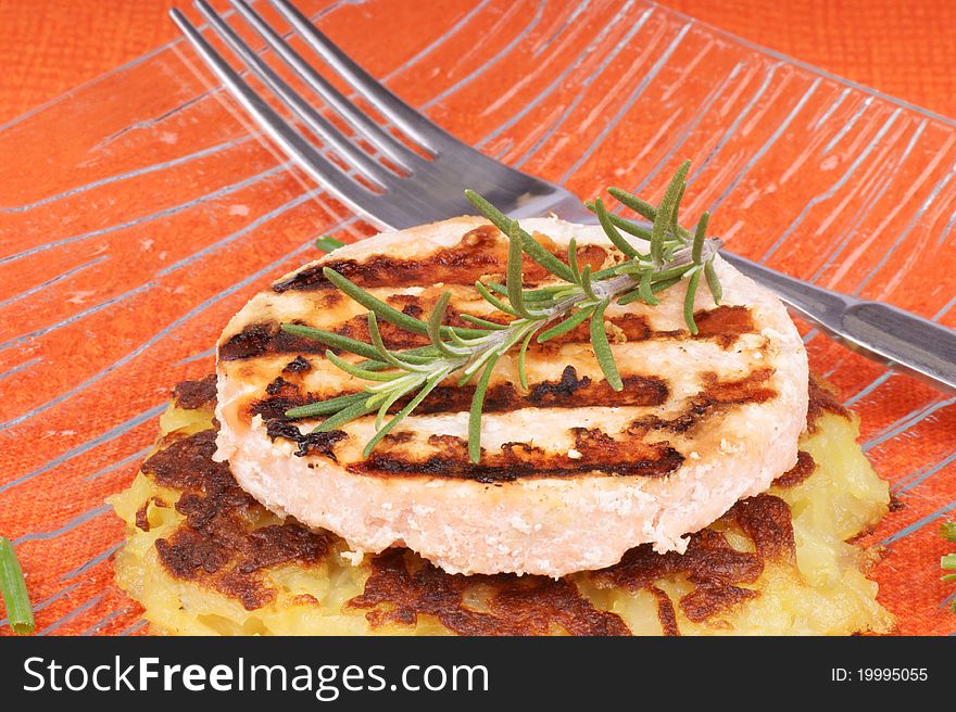 Grilled salmon and roesti with chives and rosemary over a glass dish. Selective focus, shallow DOF