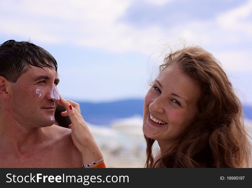 Young woman applying cream on boyfriends nose. Young woman applying cream on boyfriends nose