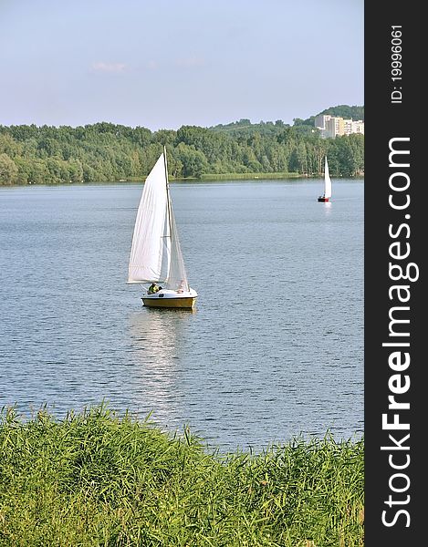 Photo shows a sailboat on the lake inland. Photo shows a sailboat on the lake inland.