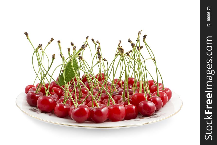 Cherry with a branch on a dish on a white background