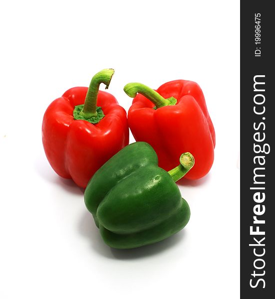 Two red and one green sweet peppers isolated on white