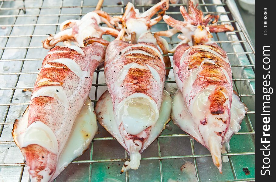 Three squid with a wooden plug. To take to the grill. Three squid with a wooden plug. To take to the grill