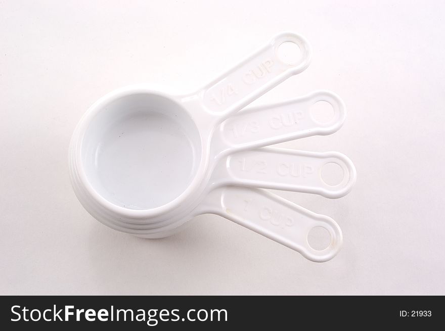 White measuring cups stacked on a white background with their handles fanned. White measuring cups stacked on a white background with their handles fanned.