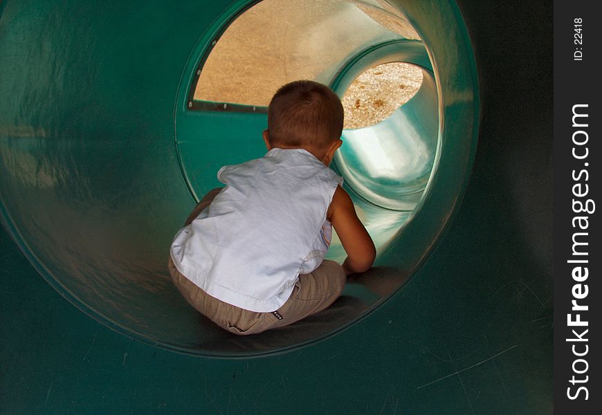 Toddler sliding down a tube slide. Toddler sliding down a tube slide