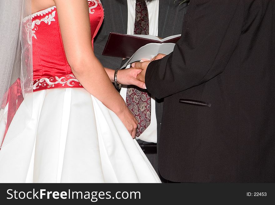 A groom placing the wedding ring on his brides finger, View shows hands and partial view of their bodies. A groom placing the wedding ring on his brides finger, View shows hands and partial view of their bodies.