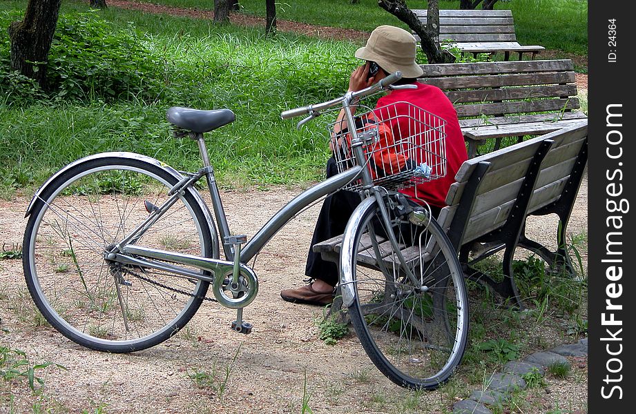 A boy sitting near his bicycle and calling someone. A boy sitting near his bicycle and calling someone