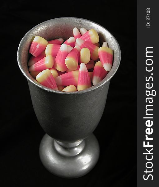 A pewter goblet full of candy corn, on a black background. A gothic look for a favorite halloween treat. A pewter goblet full of candy corn, on a black background. A gothic look for a favorite halloween treat.