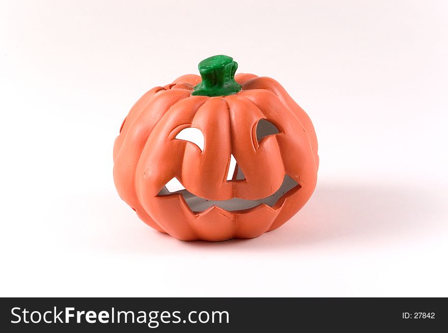 A small ceramic pumpkin decoration for Halloween. Pumpkin has jack-o-lantern face carved on it.
