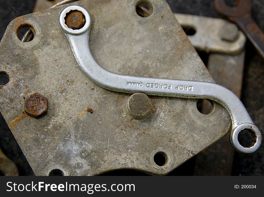 A new curved box end wrench on a old piece of equipment with a rusty bolt. A new curved box end wrench on a old piece of equipment with a rusty bolt