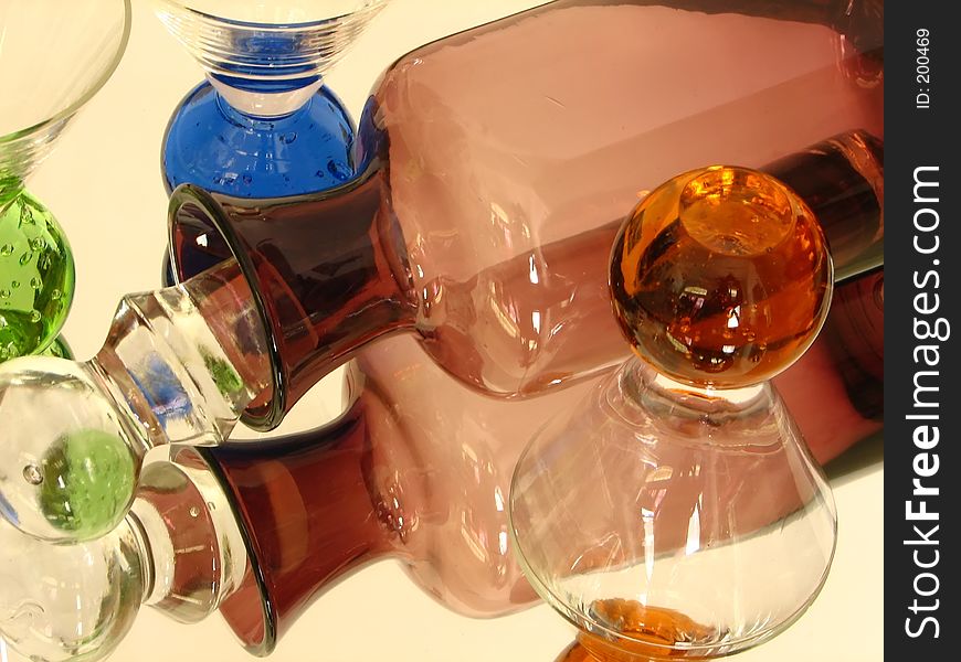 Shot of a glass bottle with some shot glasses over a mirror. white back ground. Shot of a glass bottle with some shot glasses over a mirror. white back ground.