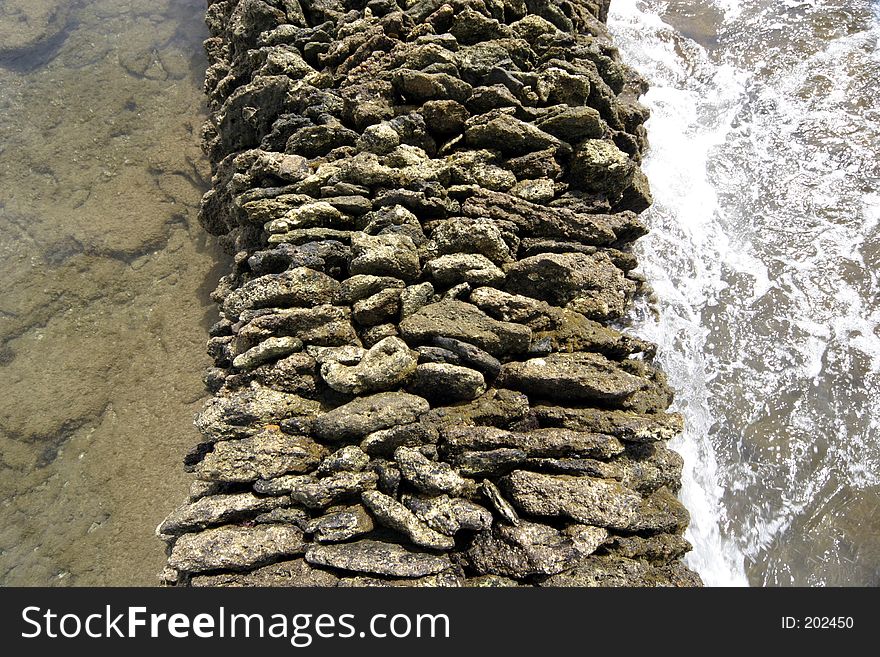 Waves breaking against a man made corral for trapping fish in ancient times. Waves breaking against a man made corral for trapping fish in ancient times