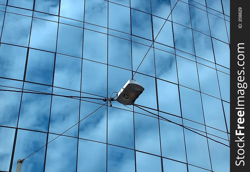 Street light with an office building in background. Glass facade is reflecting skies