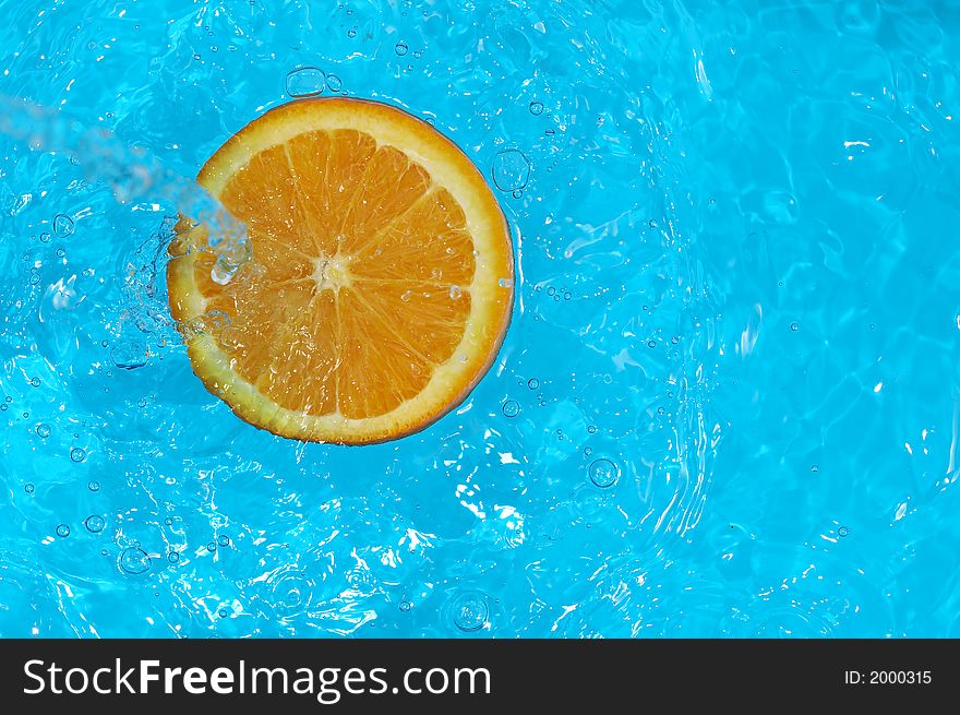 Water splashing on orange in blue water. Water splashing on orange in blue water