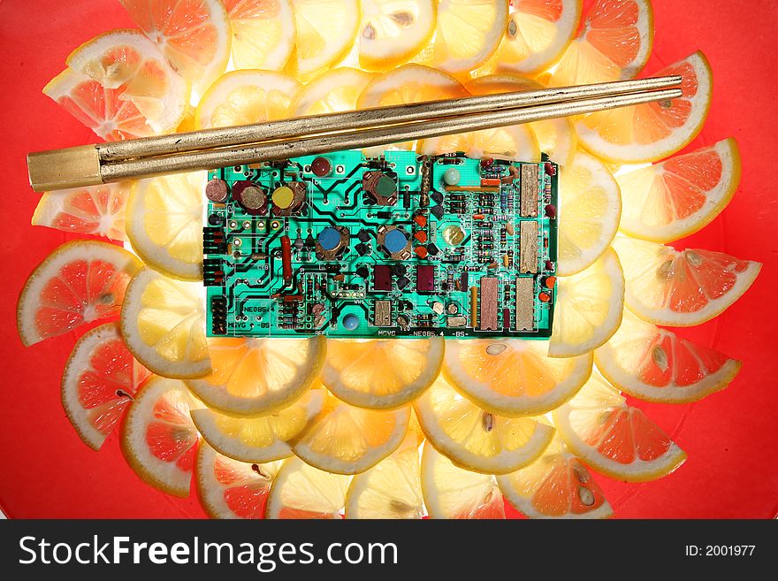 Arrangement with integrated circuit ,slices of lemon and carrot on a glass plate  with red rim,golden eating stick. Arrangement with integrated circuit ,slices of lemon and carrot on a glass plate  with red rim,golden eating stick.