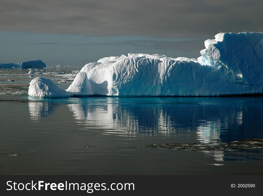 Iceberg In Sunlight With Water Reflection