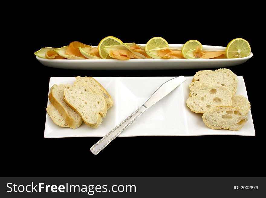 Fresh salmon cut into pieces with chicory and lemon together with bread and knife. Fresh salmon cut into pieces with chicory and lemon together with bread and knife