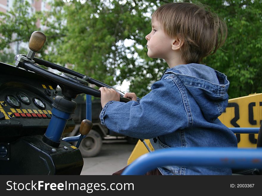 The small child would like to play with real road roller and want to look as the adult worker. The small child would like to play with real road roller and want to look as the adult worker