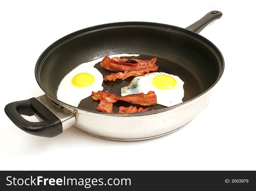 Shot of fried eggs & bacon in skillet